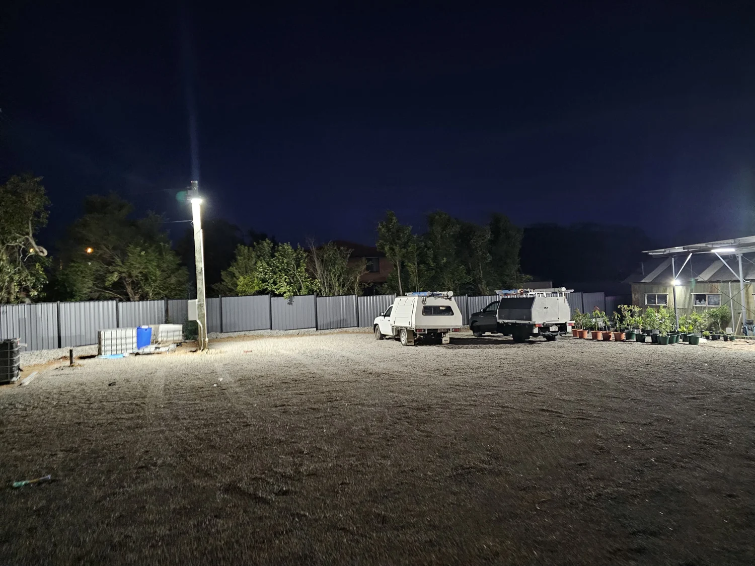 Outdoor yard illuminated by pole-mounted area lights at dusk