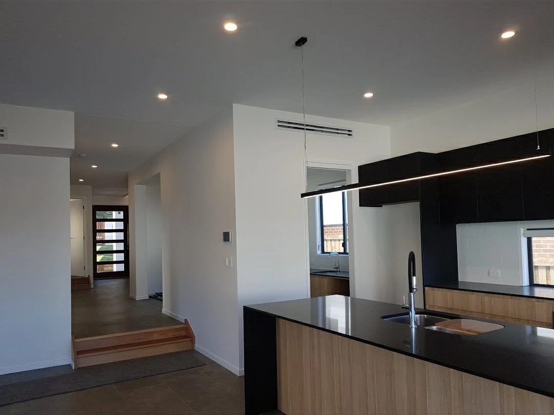 Kitchen with linear pendant lighting and downlights installed by Electrified